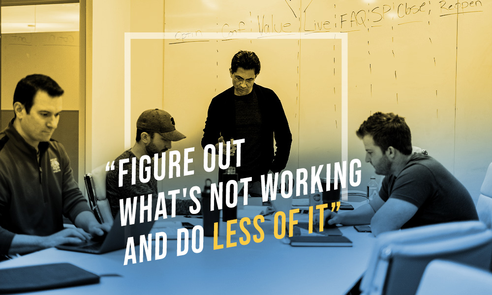Dean Graziosi and employees working at office. Text: "Figure out what's not working and do less of it."