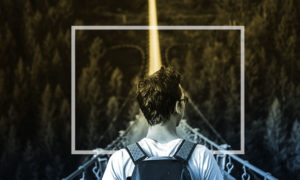 young man crossing a narrow bridge in the forest