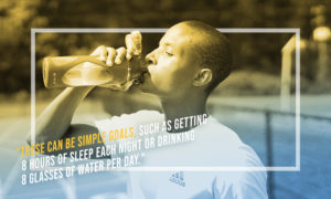 man drinking from a water bottle on a tennis court